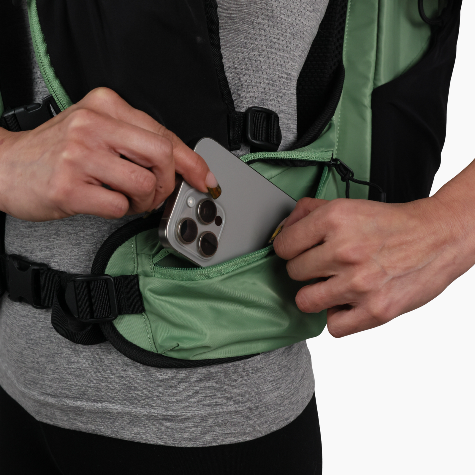 Phone being placed inside the zippered hip belt pocket of the sage green Canyon Elite 25 pack