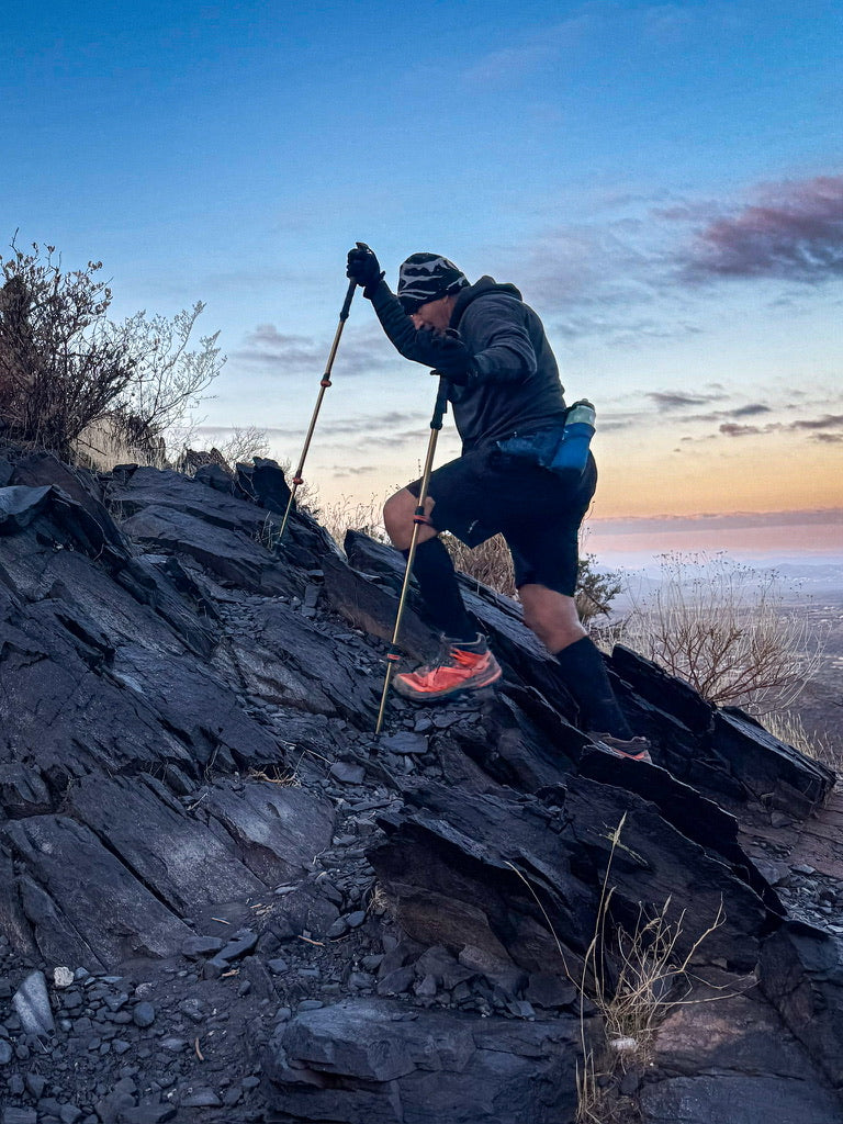 Coach Arnie Fonseca Jr. climbs a steep rocky hill using trekking poles during Grand Canyon training.