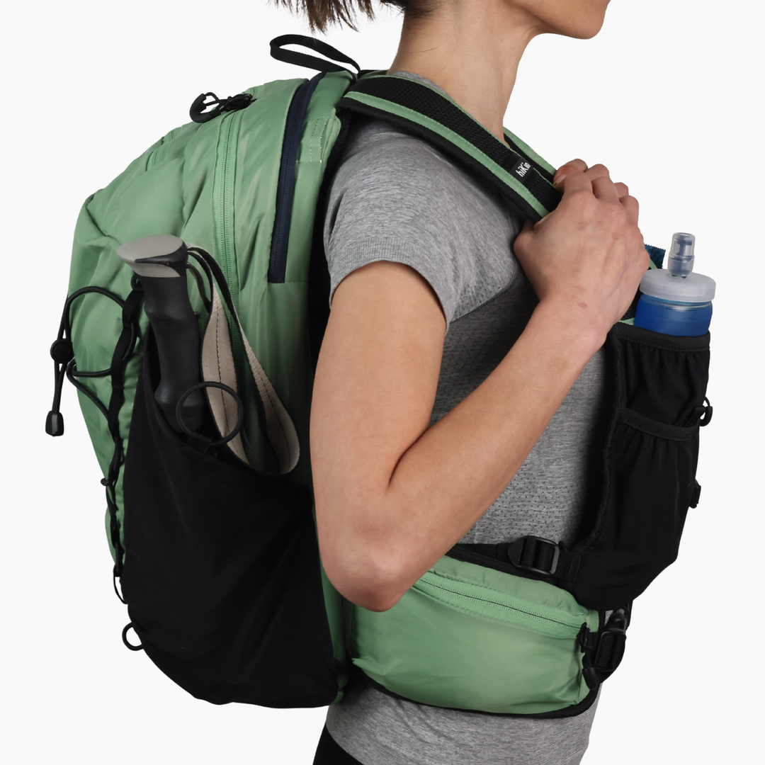 Side view of a hiker wearing the sage green Canyon Elite 25 backpack
