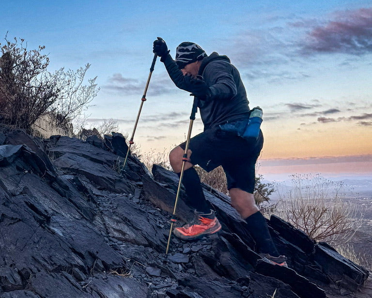 Coach Arnie training on a steep rocky hill with trekking poles
