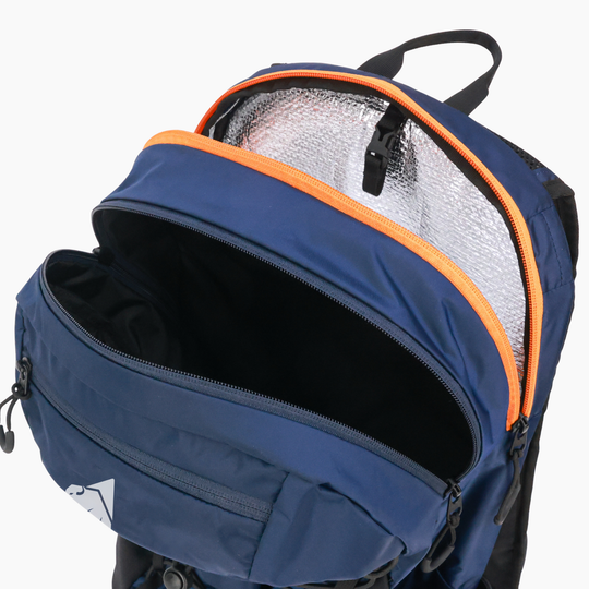 A navy blue backpack with an open front compartment showing a silver reflective lining and bright orange zipper trim, photographed on a clean white background.